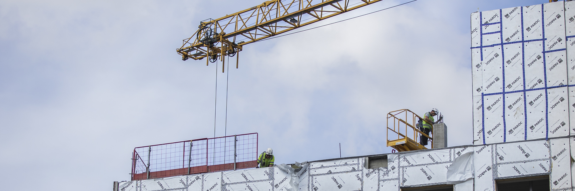 Builders building a high-rise. The jib of a tower crane is visible above.