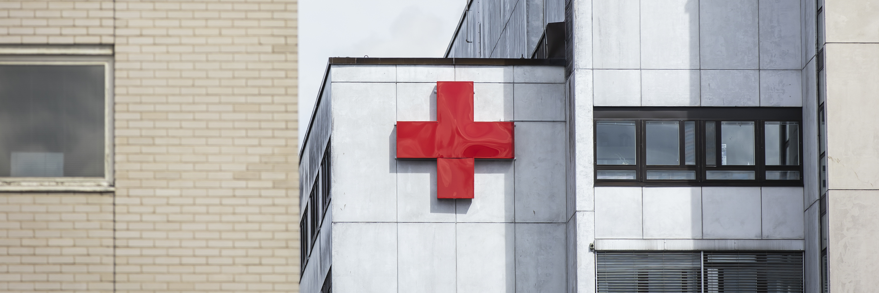 A hospital building with the Red Cross on its wall.