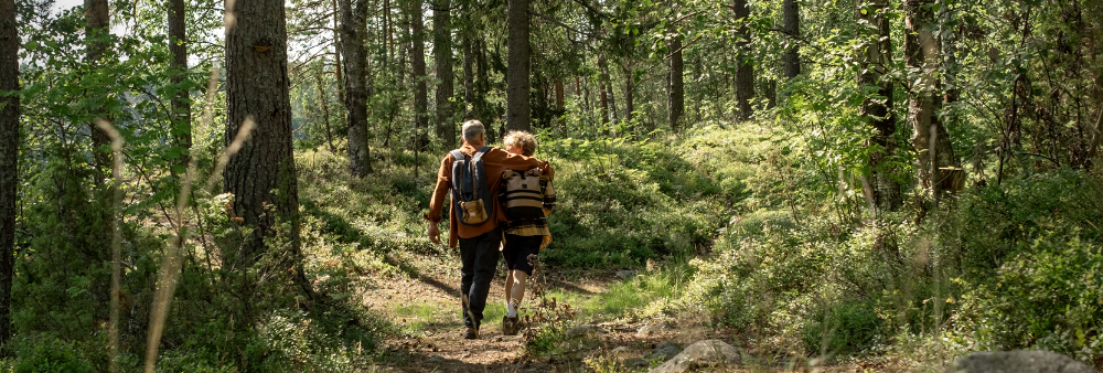 A man and a woman are walking side by side in the forest.