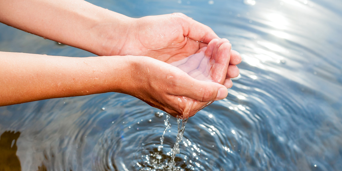 Kädet yhdessä puhtaan veden yllä.