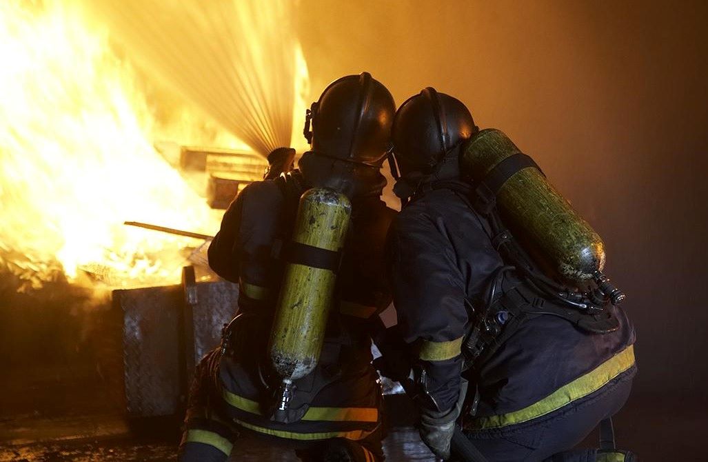 Kaksi pelastajaa sammuttamassa tulipaloa.